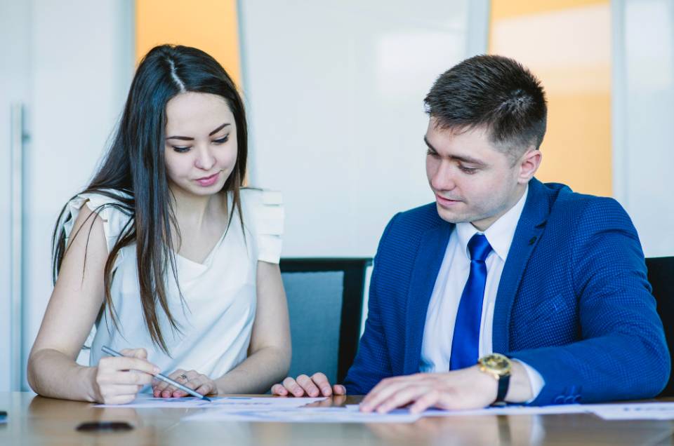 Two sitting business people looking at documents